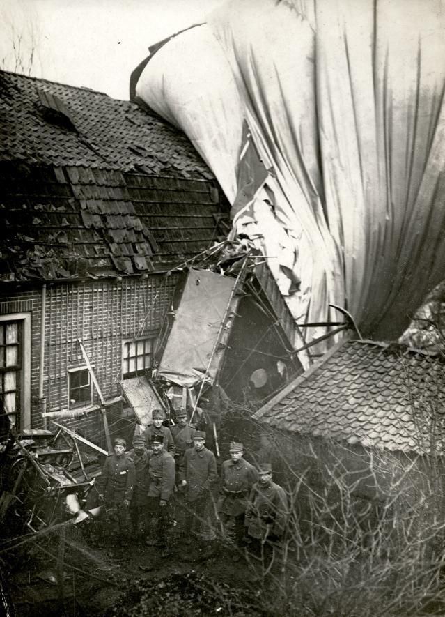 Eerste Wereldoorlog : Luchtoorlog : Schade aan huis in Eemnes, nadat zich een stuurloos Engels luchtschip / zeppelin daarin heeft geboord. Op de achtergrond de restanten van het luchtschip. Nederland, 1917.