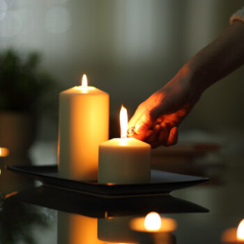 Close up of woman hand lighting candles in the dark night at home