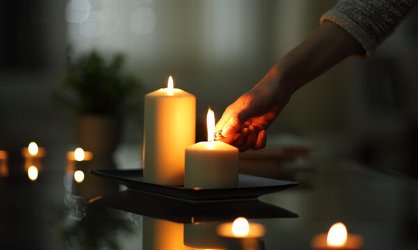 Close up of woman hand lighting candles in the dark night at home