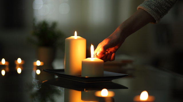 Close up of woman hand lighting candles in the dark night at home